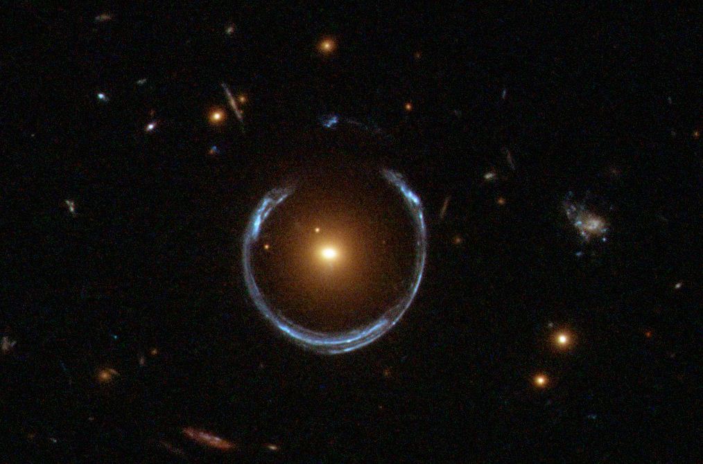 Eine rötlich/gelbliche Galaxie im Vordergrund lenkt durch ihre Masse Licht von einer hinter ihr liegenden, bläulichen, Galaxie ab was in der beobachteten Hufnagelform resultiert. Ein durch das Hubble Teleskop beobachtetes Beispiel für den durch die allgemeine Relativitätstheorie vorhergesagten Gravitationslinseneffekt. A Horseshoe Einstein Ring from Hubble by Lensshoe_hubble.jpg: ESA/Hubble & NASAderivative work: Bulwersator (talk) - Lensshoe_hubble.jpg. Licensed under Public Domain via Commons.